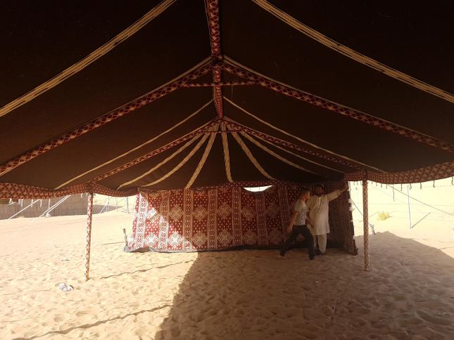 Bedouin tent interior with a central pole, decorative supports and patterned fabric wall; located in the Middle East