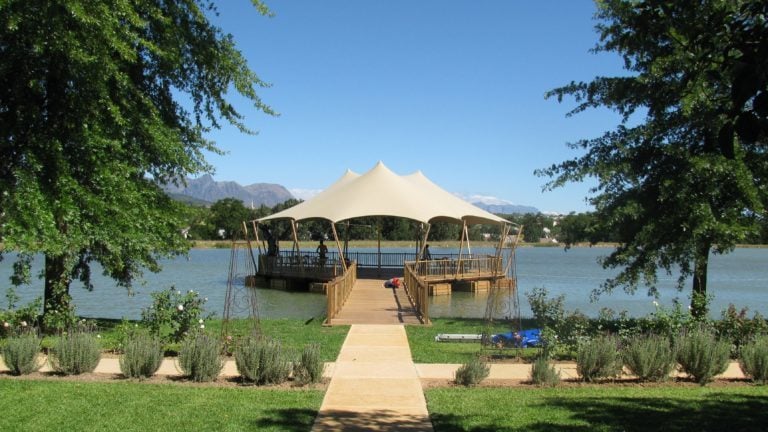 Beige Custom Stretch Tent on a lakeside platform reached by a wooden walkway