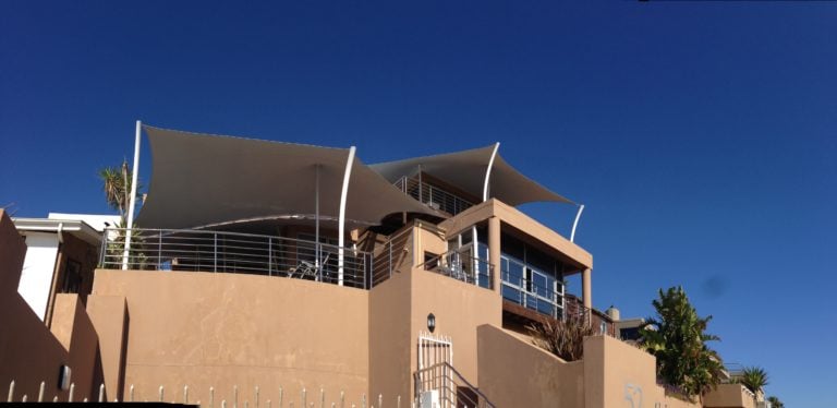 Beige bespoke stretch tent canopy shading a rooftop terrace on a coastal building for a residential area