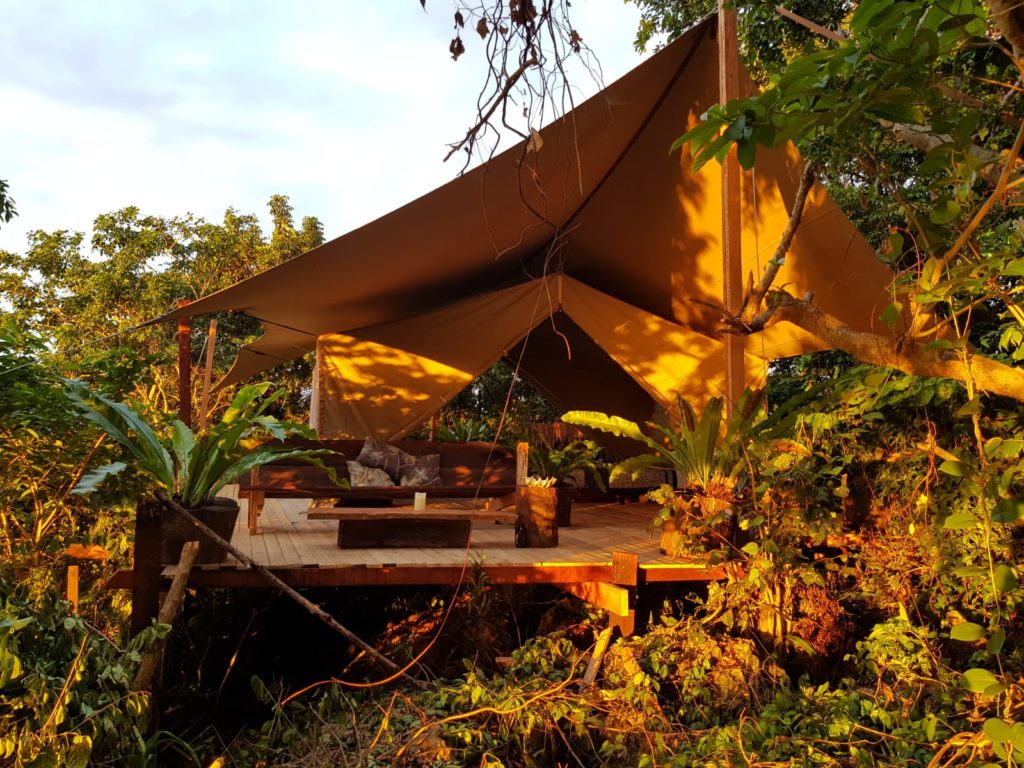 Beige RHI Glamper Stretch Tent unit sheltering a timber glamping deck among trees