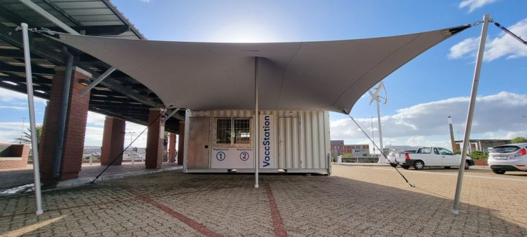Een witte, op maat gemaakte stretch-overkapping die de ingang van een omgebouwde zeecontainer beschermt