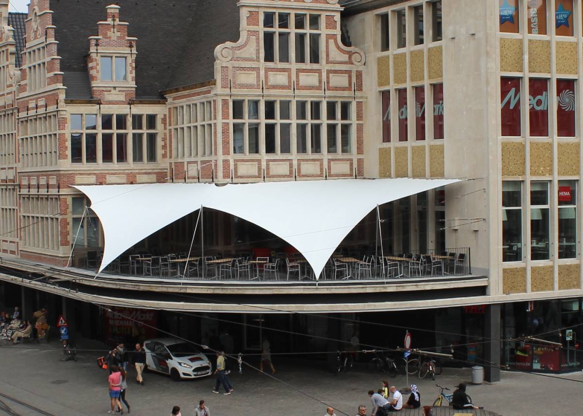 Ein maßgefertigtes, weißes „ Stretchzelt “-Modell, das an einem Balkon eines kunstvoll gestalteten städtischen Gebäudes in Belgien angebracht wurde