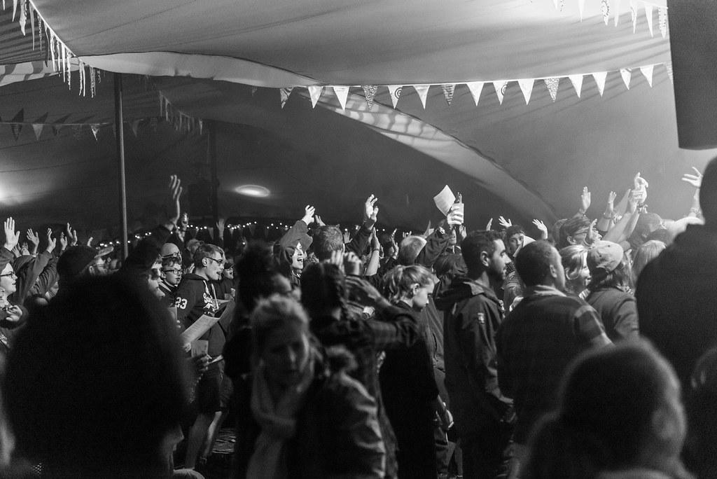 Zwart-witfoto van een festivalpubliek onder een grootschalige, modulair opgebouwde Stretch Tent; gelegen in het Verenigd Koninkrijk