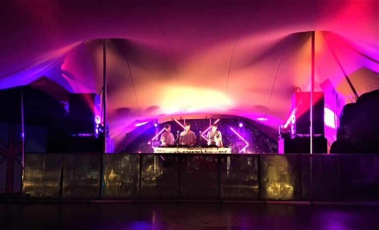 Festivalpodium onder een Flextent in Duitsland, ’s nachts verlicht in roze, paars en oranje