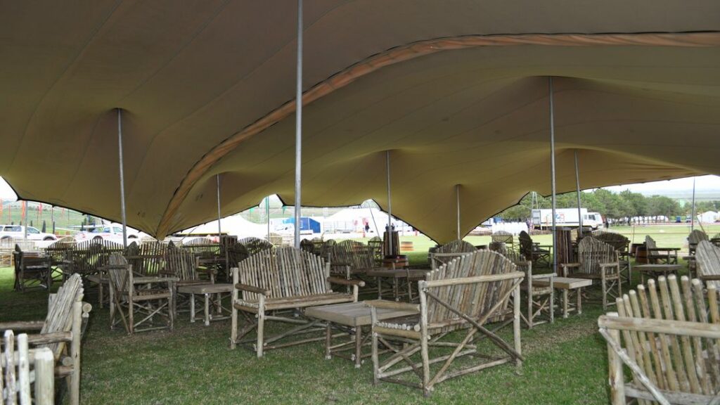 grootschalige, modulair met elkaar verbonden stretch-tenten die de picknicktafels en -banken op een festival overkappen