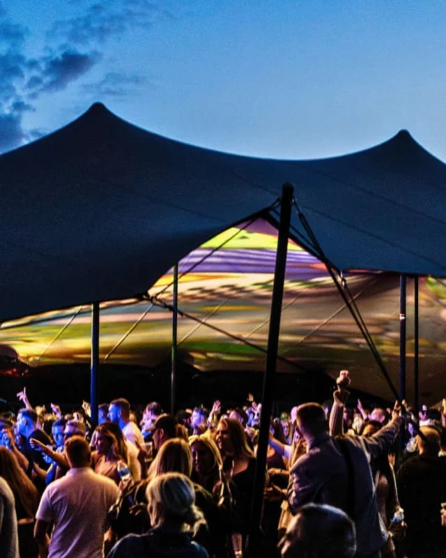 Crowd gathered beneath a Large RHI stretch tent at a live festival in the United Kingdom