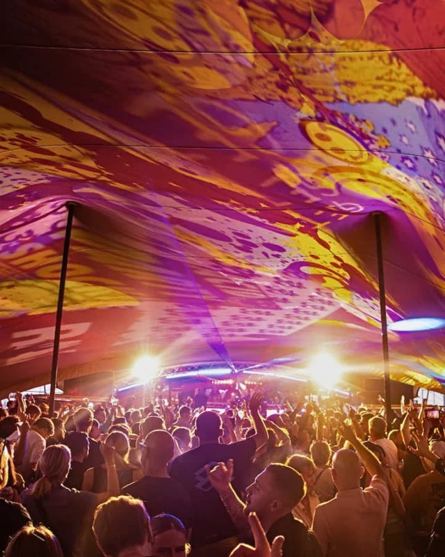 Festival crowd beneath a Large Scale RHI stretch tent illuminated with stage lighting in the United Kingdom