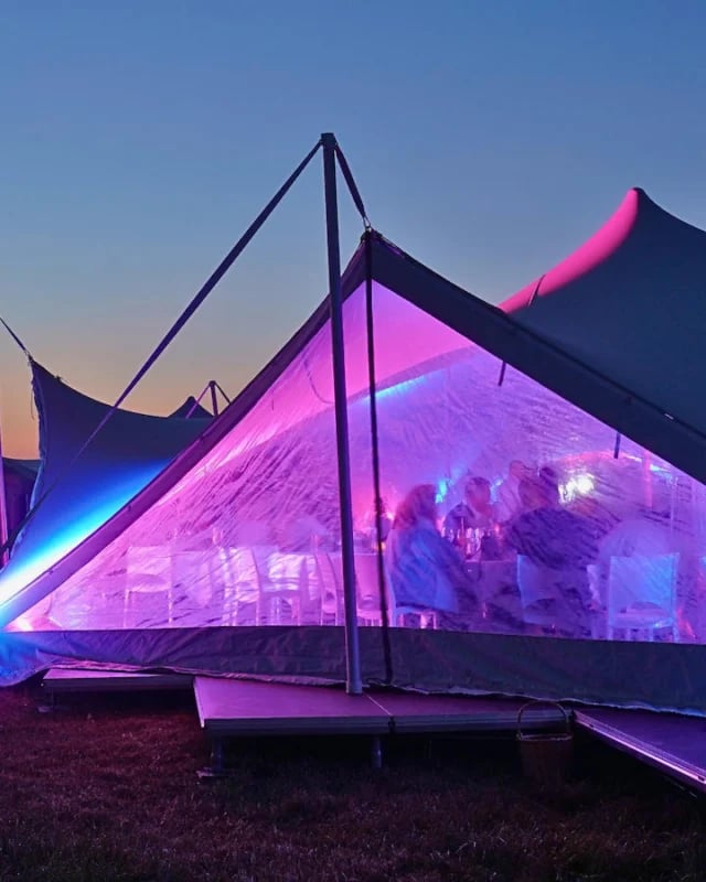 RHI Arachnid Series Festival stretch tent with Closing Down Sealing Doors glowing pink and blue during an evening festival