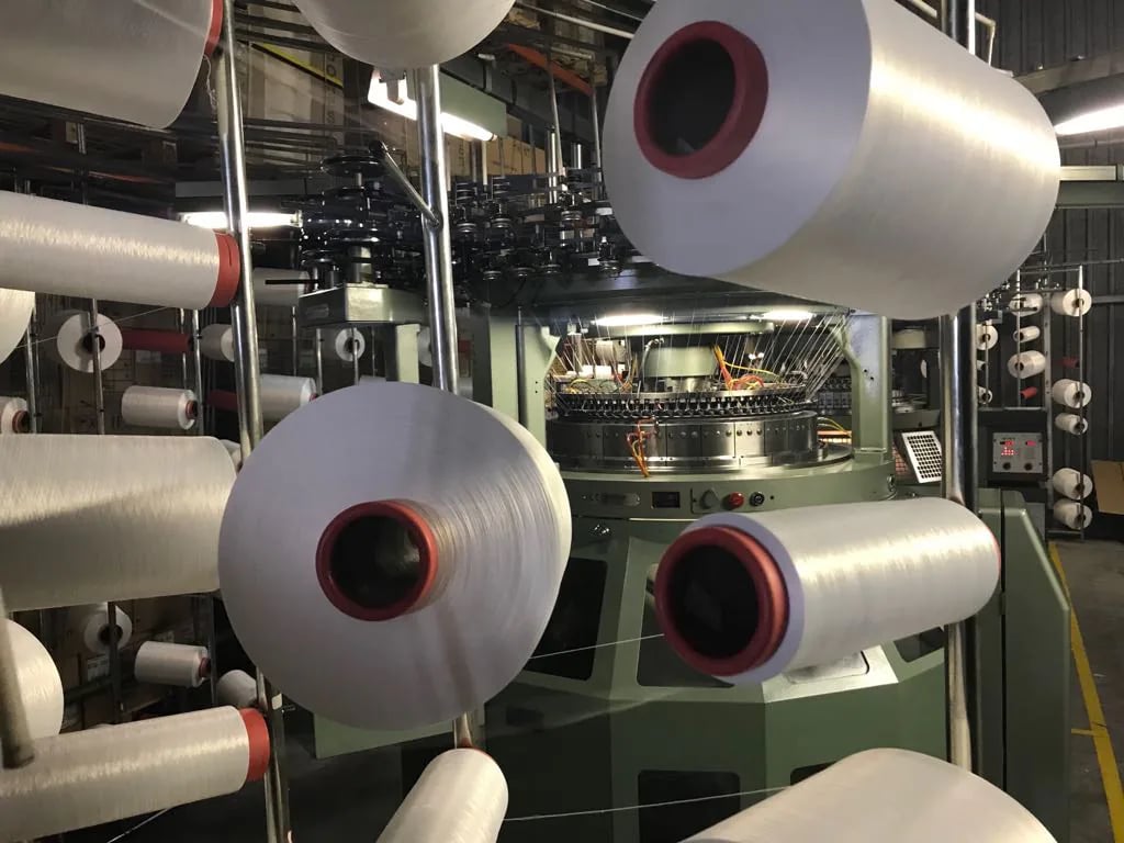 In-house knitting machine producing stretch tent fabric