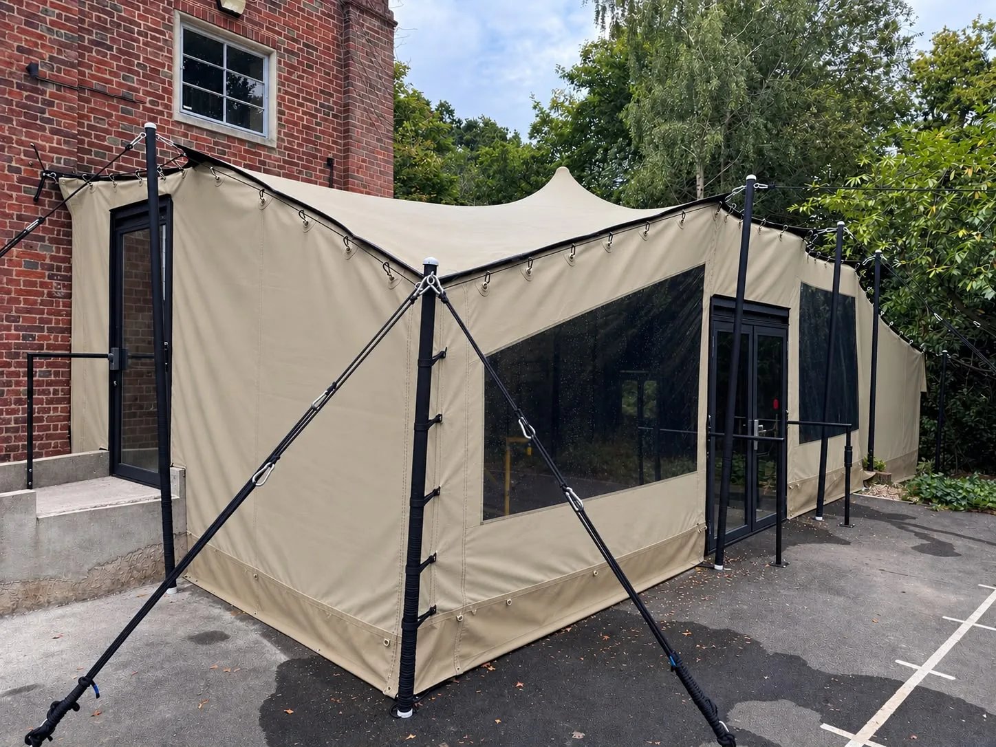 Custom stretch tent with walling adjoining a brick building