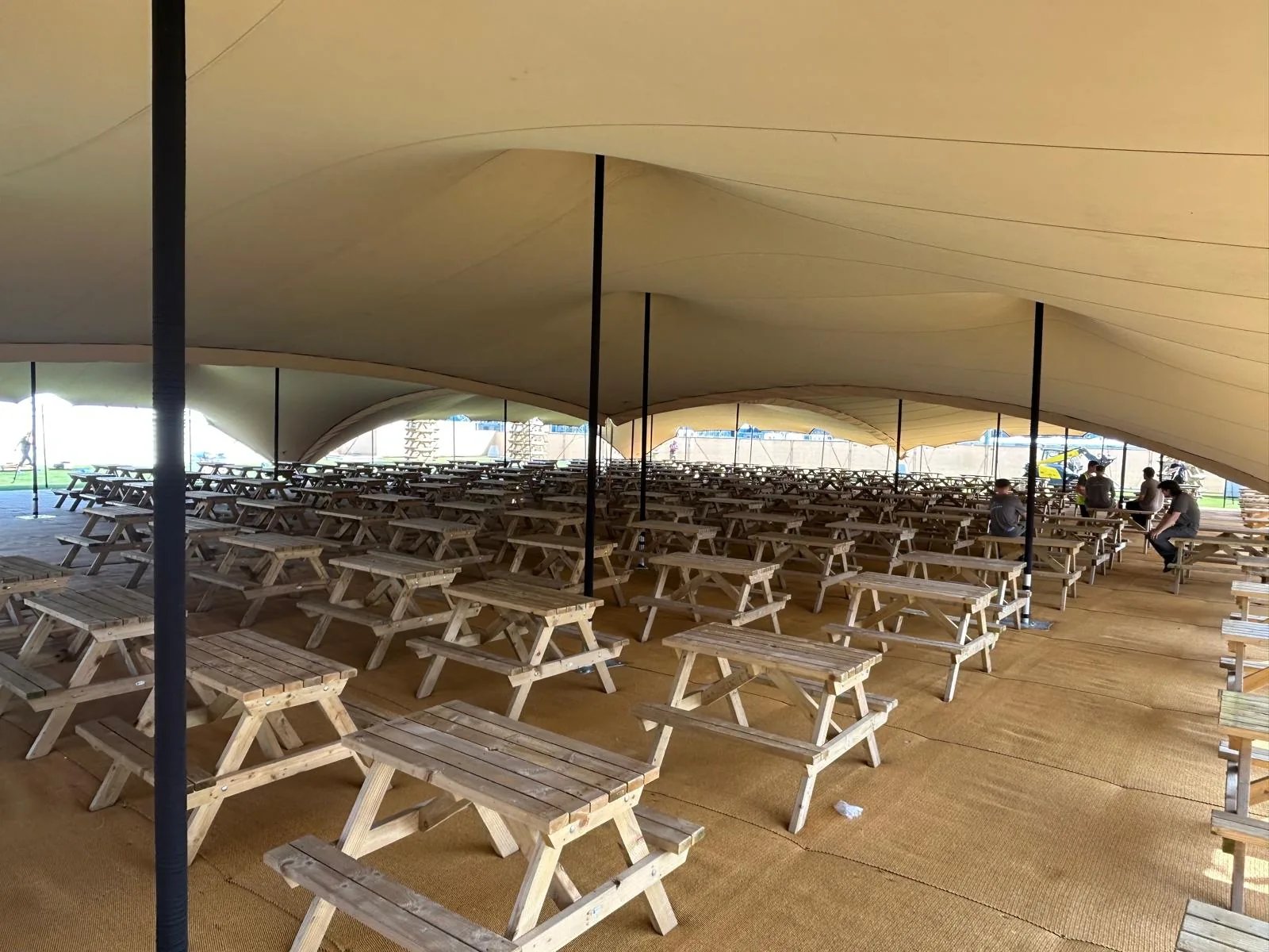 Picnic tables beneath four linked RHI stretch tents