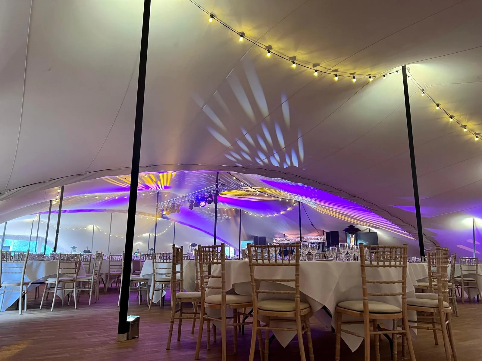 Linked stretch tents with clear walling and colourful evening lighting