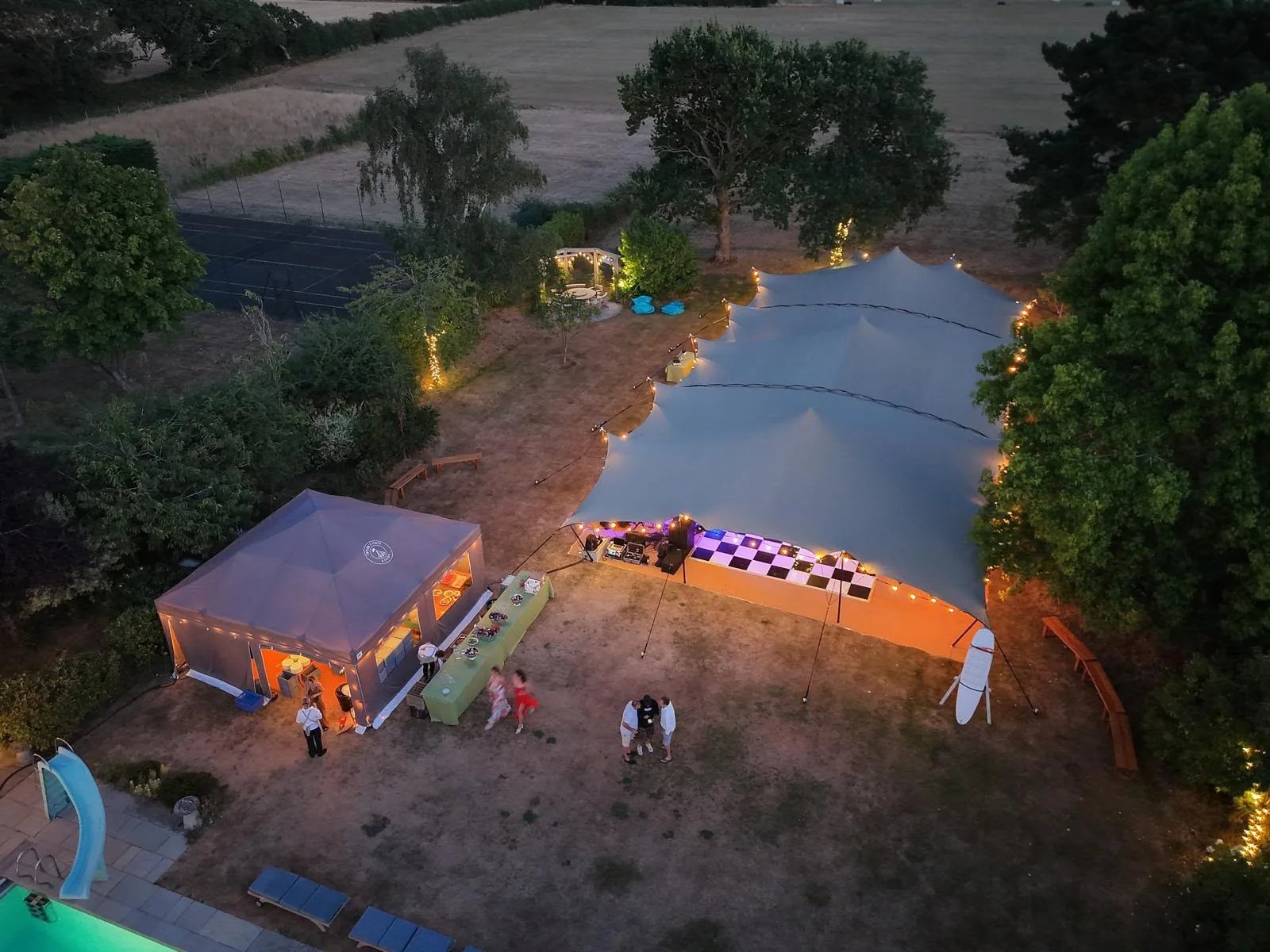 Linked RHI stretch tents illuminated at an outdoor event at night