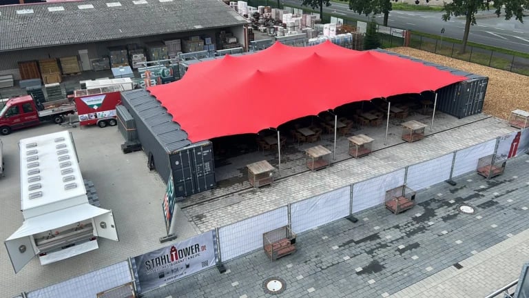Aerial view of a red stretch tent between container units — 50 m² Red Stretch Tent for a Container Venue in Germany
