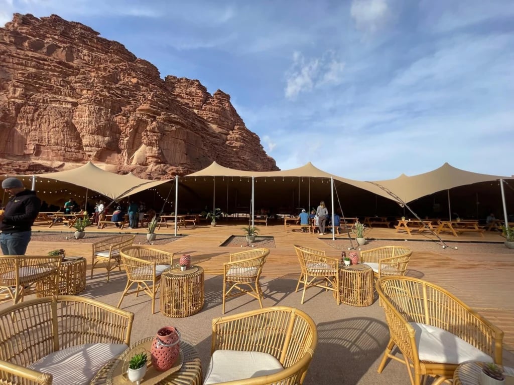 stretch tent sections and outdoor seating below desert rock formations — Linked Stretch Tent Hospitality for the Saudi Games