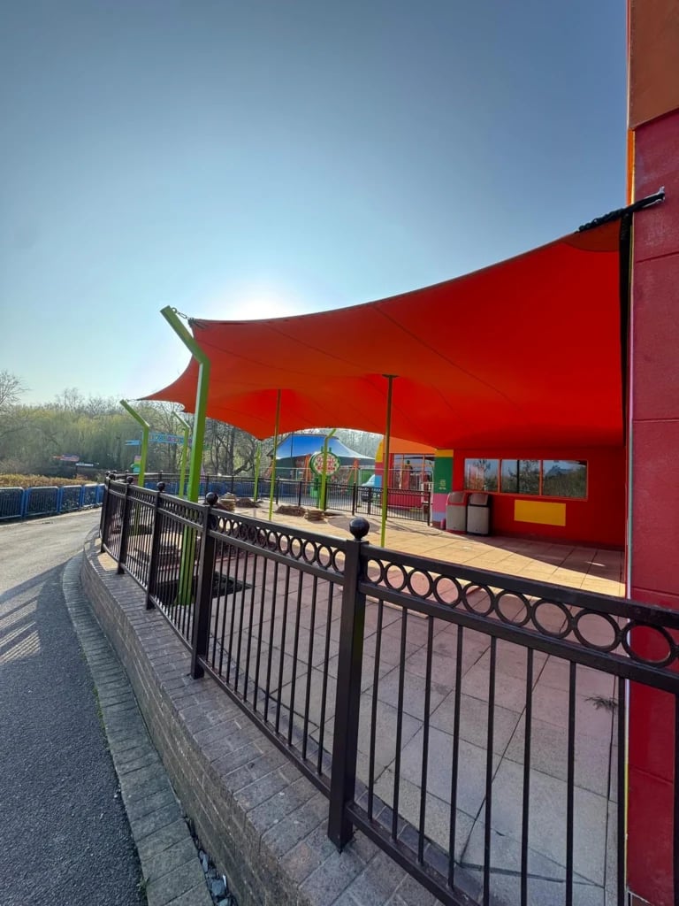 Solid red hypar stretch tent beside a visitor route — Custom Stretch Tents at LEGOLAND Windsor, UK