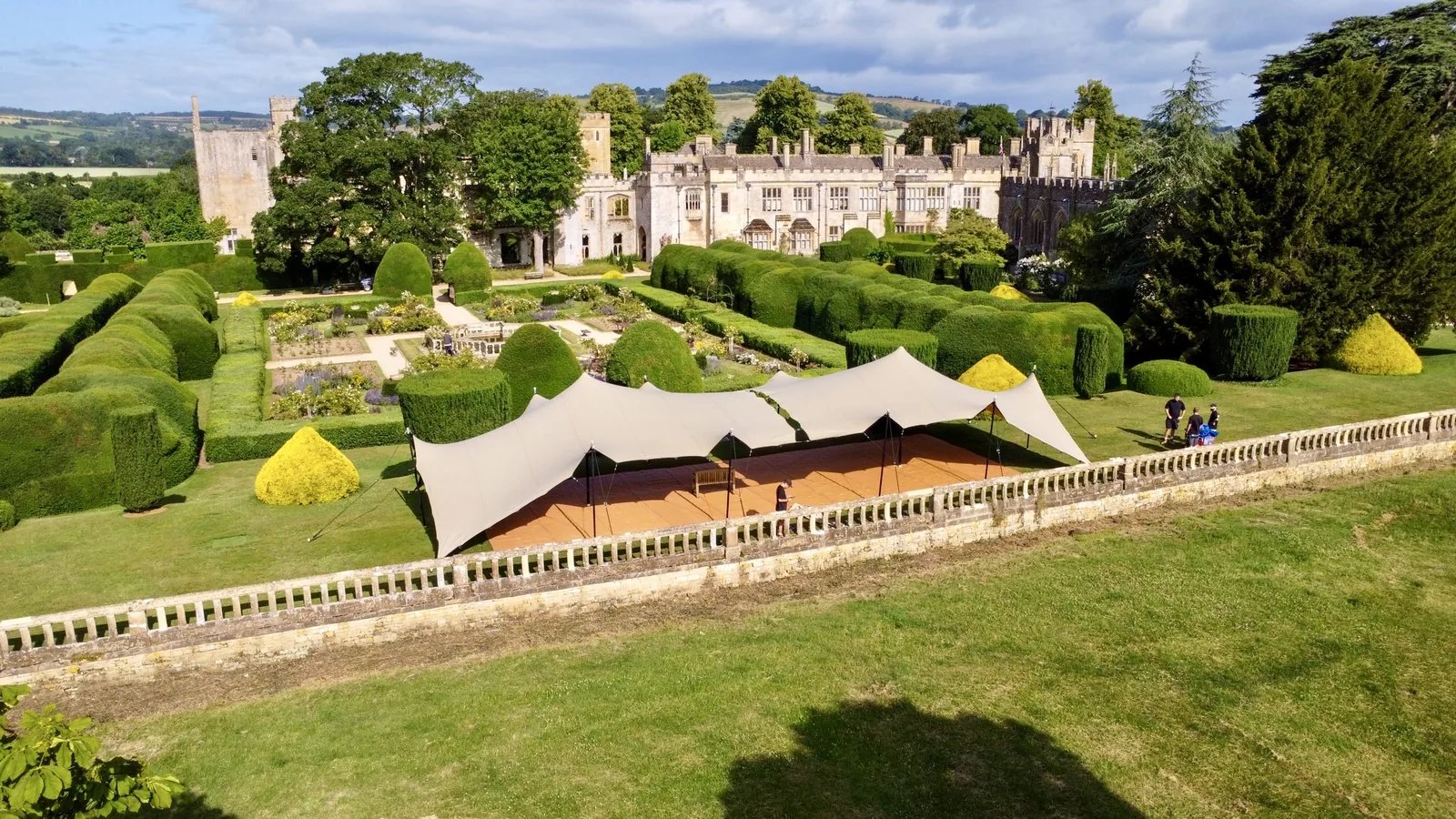 Two linked chino RHI stretch tents with corners down on an estate lawn