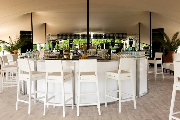 Vue centrale du bar d'un établissement « tente stretch » de la chaîne RHI, équipé de sièges de salon et de restauration