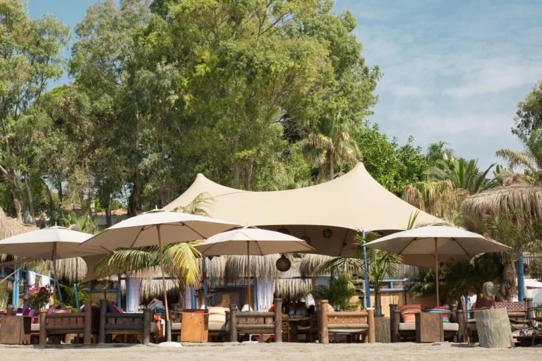 Vista frontal de la zona de recepción de un sistema RHI Carpa Tensada a medida, integrado en un restaurante frente al mar