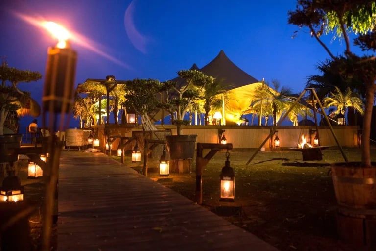 Vista nocturna de un sistema RHI Carpa Tensada a medida integrado en un restaurante frente al mar