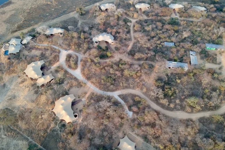 Vista aérea panorámica del campamento, en la que se aprecia una serie de tiendas de glamping de lujo personalizadas de RHI Carpas Tensadas integradas en un campamento ecológico aislado.