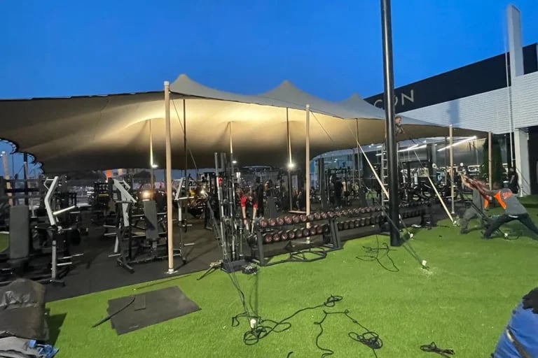 Vista lateral nocturna de una cubierta « Carpa Tensada » de RHI, fabricada a medida, que cubre un gimnasio al aire libre y una zona de entrenamiento en España