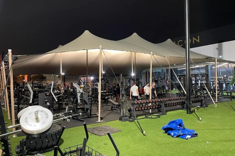 Amplia vista nocturna de un sistema « Carpa Tensada » de RHI, diseñado a medida, que cubre un gimnasio al aire libre y una zona de entrenamiento en España