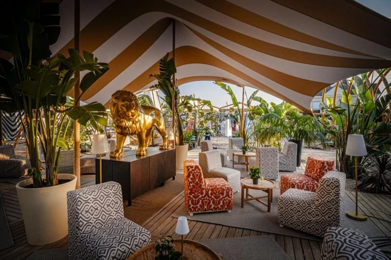Amplia vista del salón de una cortina a medida de RHI Carpa Tensada , con diseño a rayas, que cubre la terraza amueblada de un restaurante en Europa