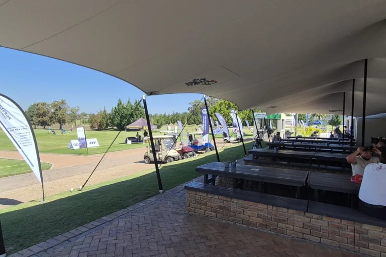 Vista desde el bar y la terraza de una cubierta « Carpa Tensada » de RHI, fabricada a medida, que cubre la zona de asientos y de restauración de un campo de golf.