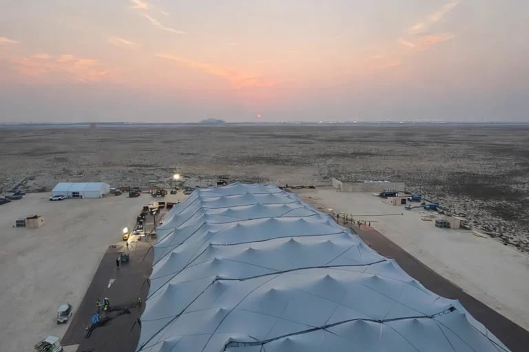 Vista aérea a lo largo de la línea del tejado de una gran estructura « Carpa Tensada » de RHI, fabricada a medida y sostenida por un sistema de vigas, en un recinto para eventos situado en el desierto