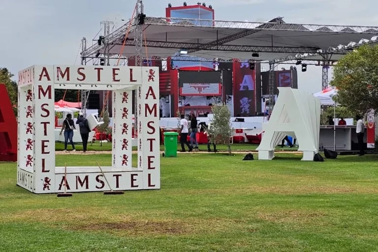 Vista frontal de una amplia zona dedicada a un evento al aire libre de una marca, con estructura de truss para el escenario, gradas e infraestructura de hospitalidad