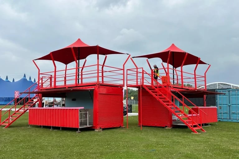 Vista exterior en ángulo de un recinto con contenedores de color rojo con el logotipo de la marca, rematado con marquesinas personalizadas de RHI Carpa Tensada