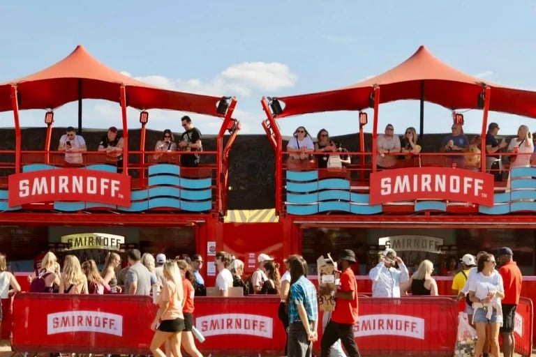 Imagen de un festival muy concurrido en el que se ve un recinto instalado en un contenedor con la marca en rojo, coronado por toldos personalizados de RHI Carpa Tensada