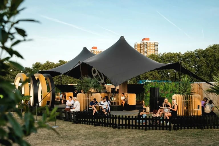 Imagen de un evento paralelo en el que se muestra una estructura de trusses y un « Carpa Tensada » negro personalizado de RHI, utilizada en un festival público en el Reino Unido