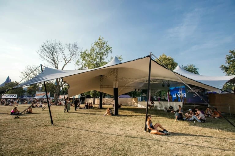 Vista general desde la zona de espectadores de una estructura de celosía y un « Carpa Tensada » blanco a medida de RHI, utilizada en un festival público en el Reino Unido