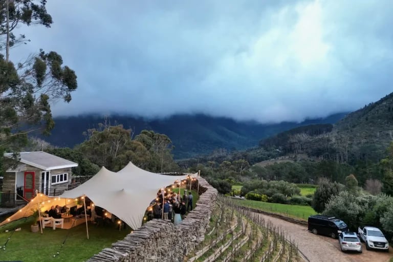Vue panoramique sur un paysage de montagne mettant en scène une installation RHI tente stretch servant de cadre à un événement public ou privé en plein air