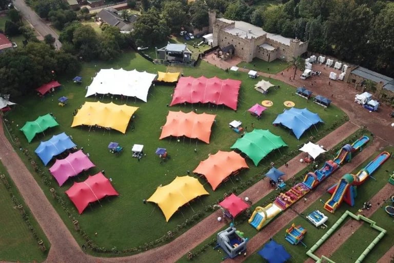 Vue aérienne de plusieurs « tentes stretch » RHI aux couleurs vives, réparties sur le site d'un festival familial en Afrique du Sud