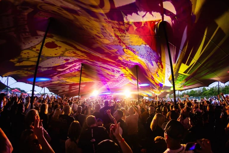 Vue imprimée de la verrière et de la foule rassemblée lors d'un festival, sous un grand « RHI » tente stretch , avec l'éclairage de la scène