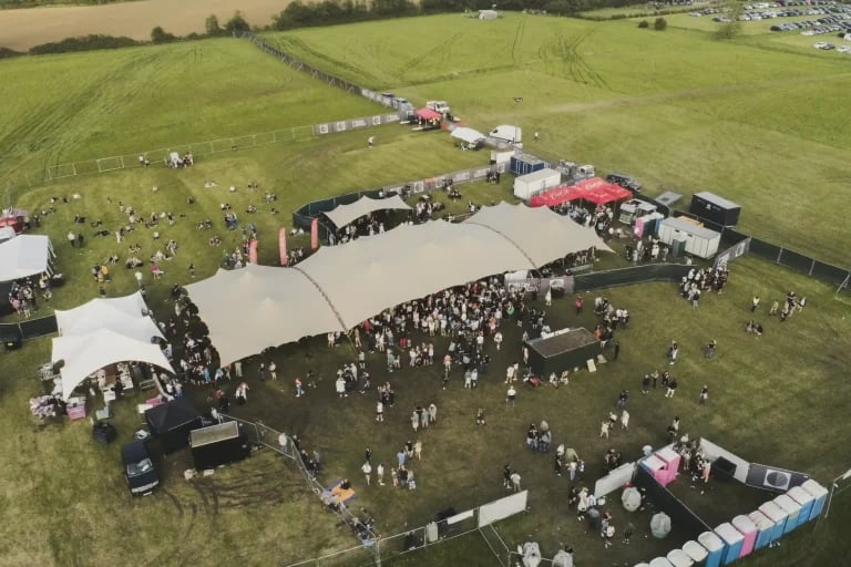 Vue aérienne d'ensemble montrant plusieurs installations RHI tentes stretch reliées entre elles sur un vaste site de festival