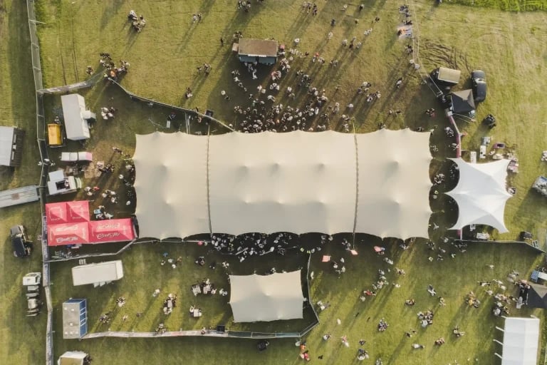 Vue aérienne verticale du toit montrant plusieurs installations RHI tentes stretch reliées entre elles sur un vaste site de festival