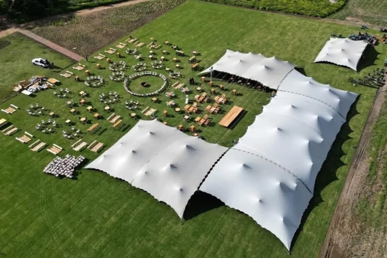 Vue aérienne d'une grande « tente stretch » grise de RHI, assemblée en série, mise en place pour un événement en plein air