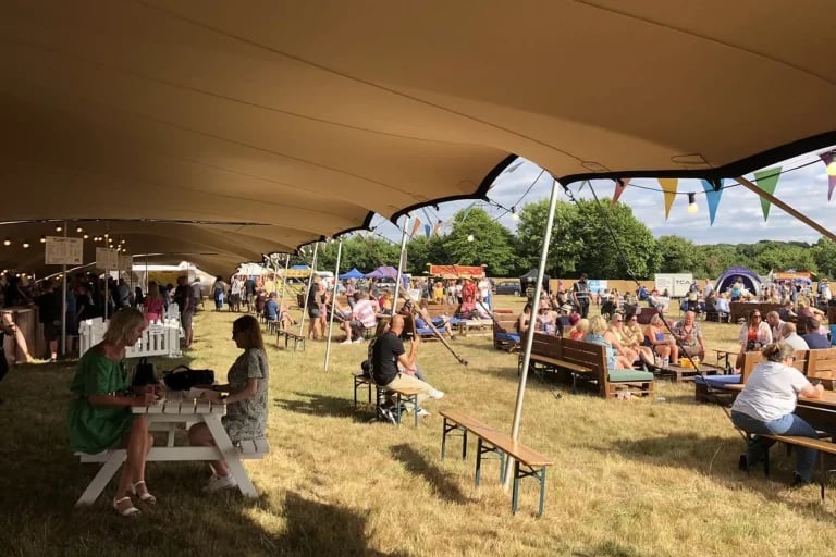 Vue intérieure de la salle à manger, avec un revêtement « tente stretch » de RHI aux teintes sombres recouvrant l'espace dédié aux repas et aux places assises du festival