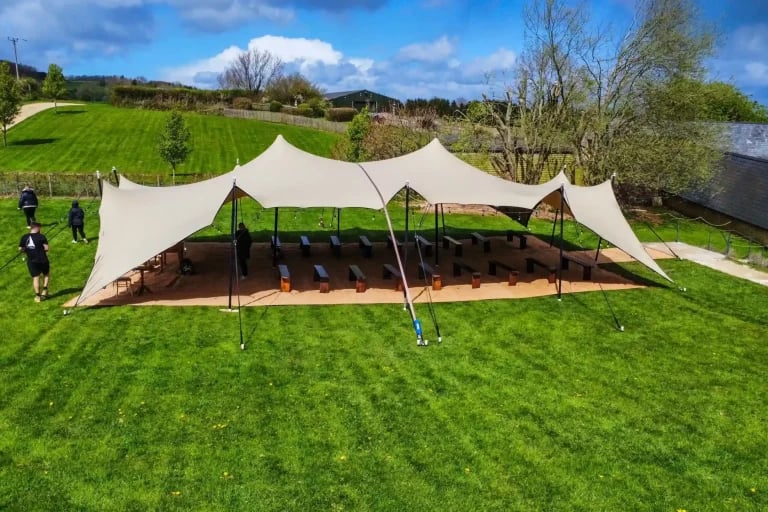 Vue en plongée sur un chapiteau de taille moyenne de l'tente stretch RHI, aménagé pour une garden-party ou une réception privée