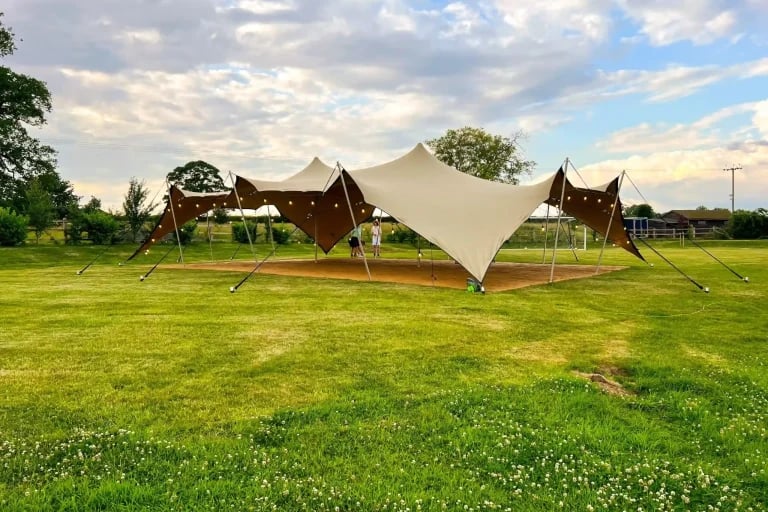 Vue extérieure de jour d'une installation « RHI » ( tente stretch ) installée dans une cour-jardin paysagée