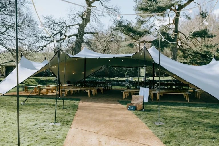 Vue de face d'une installation « RHI tente stretch », avec ses panneaux noirs et blancs contrastés, mise en place à l'occasion d'un événement dans un jardin boisé