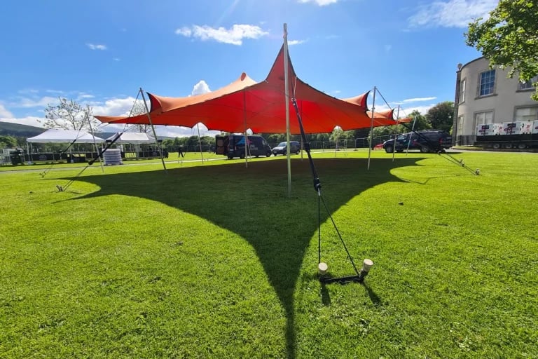 Vue latérale panoramique d'une grande installation RHI tente stretch de couleur orange, installée sur une pelouse soignée en Irlande