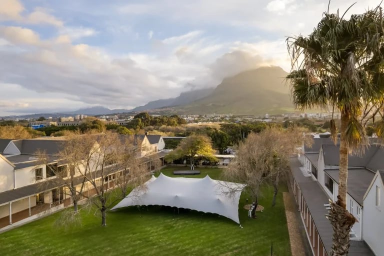 Vue aérienne vers les montagnes d'une grande installation RHI tente stretch de couleur grise, implantée au sein d'un campus universitaire ou institutionnel