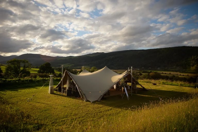 Extérieur au coucher du soleil dans un paysage rural d'une propriété « RHI » tente stretch au Royaume-Uni, aménagée pour un mariage ou une réception en plein air