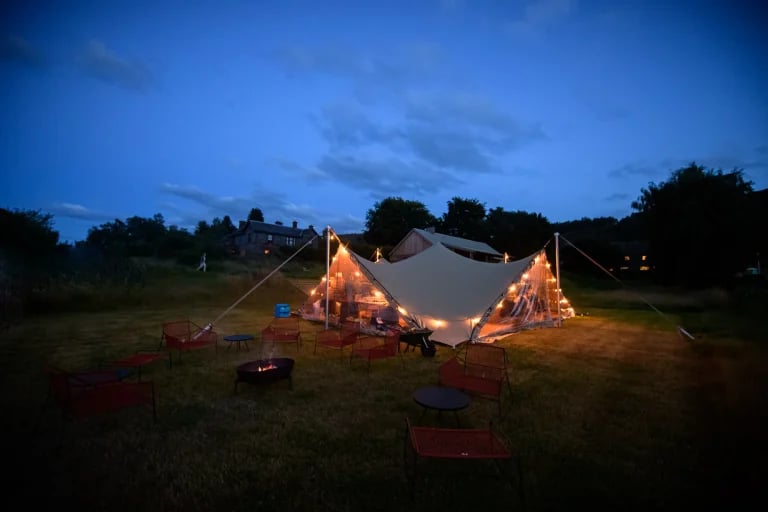 Vue panoramique nocturne d'une réception organisée au « Walled RHI » tente stretch , aménagée pour un mariage ou une réception en plein air