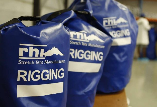 Blauwe RHI-zakken met het opschrift „RIGGING”, gevuld met tentuitrusting